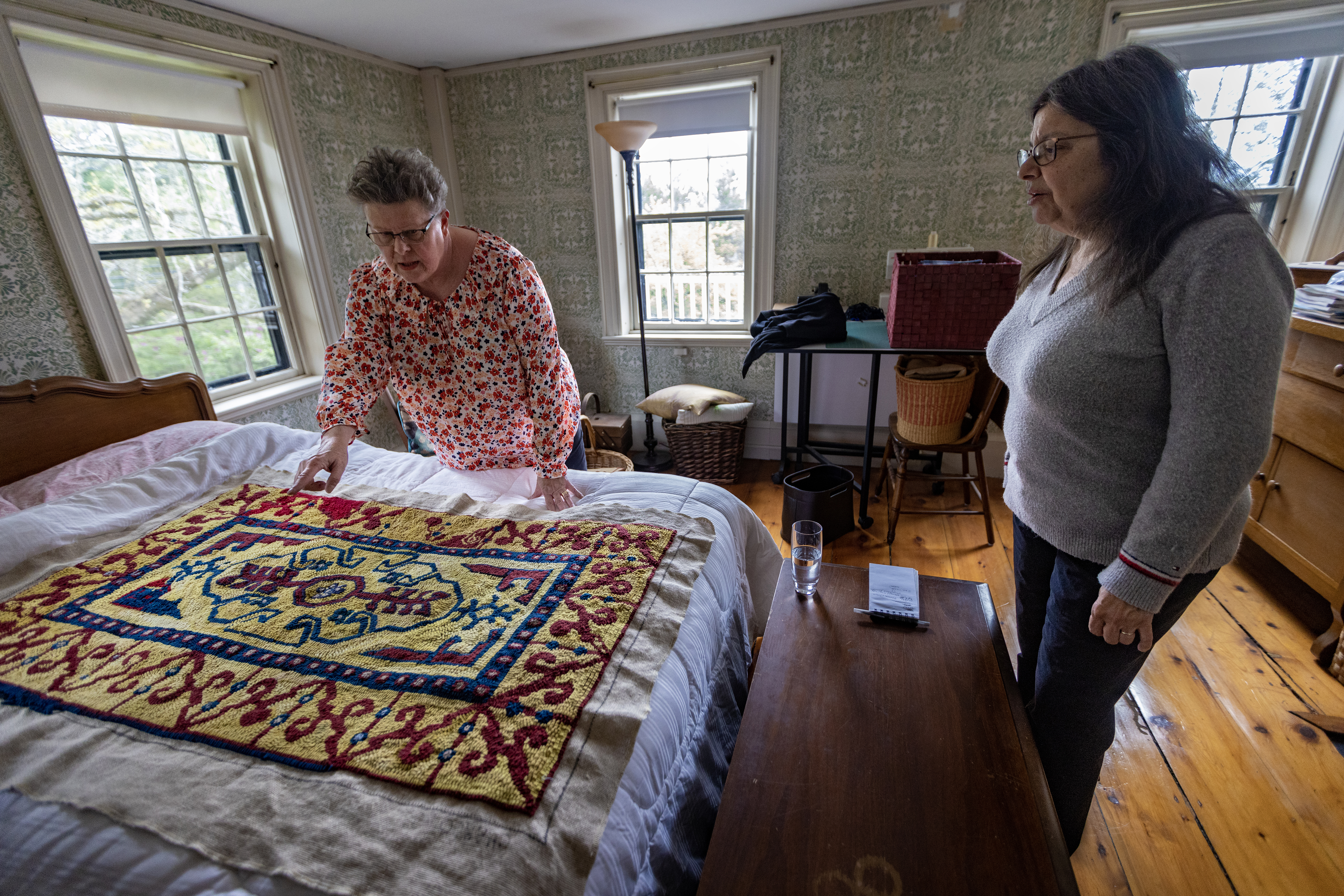 Jan Rohwetter examines the stitching patterns Donna Savastio has used in the rug she started.