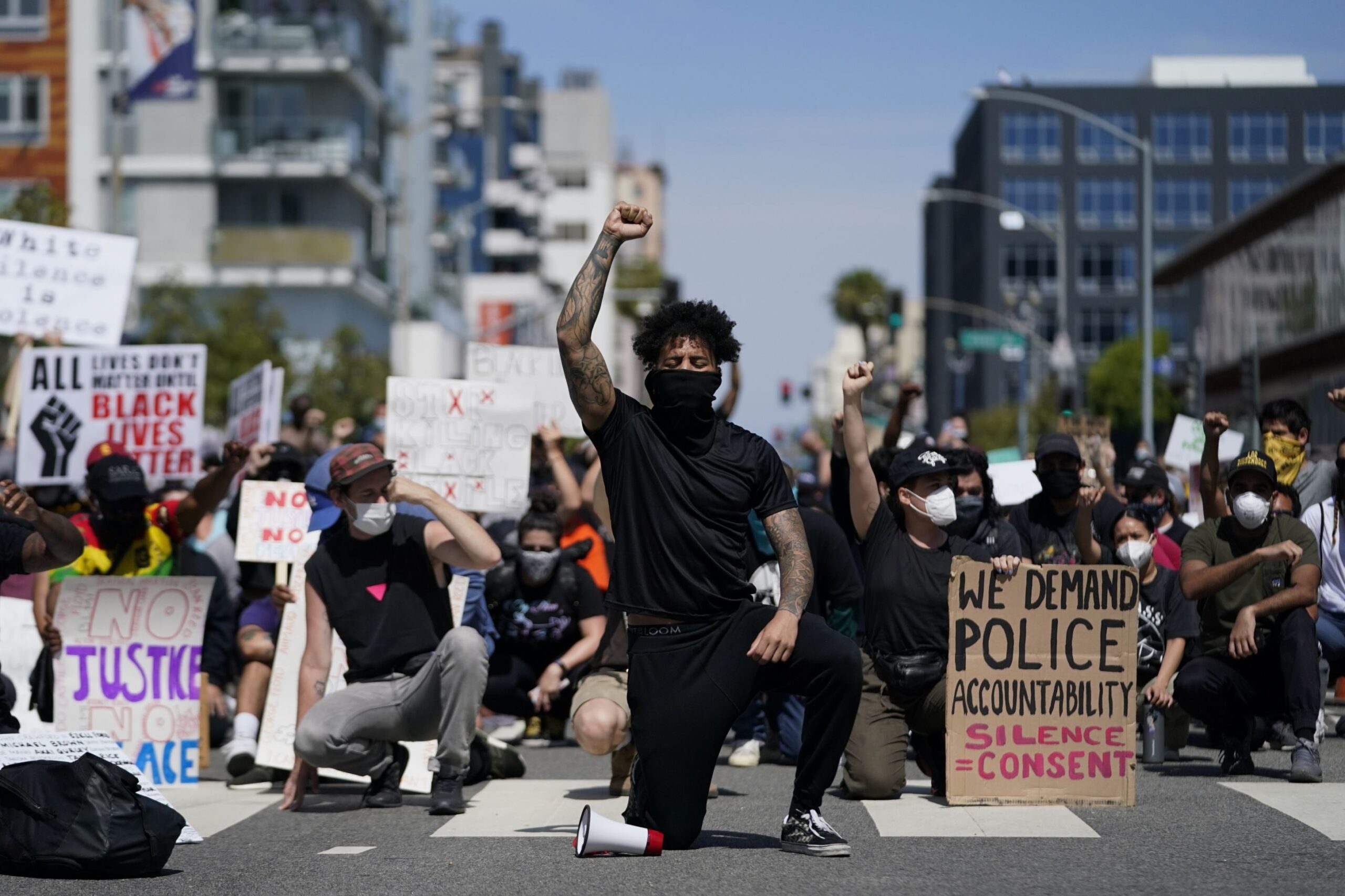 Demonstrators kneel in a moment of silence outside the Long Beach Police Department on Sunday, May 31, 2020, in Long Beach during a protest over the death of George Floyd. Protests were held in U.S. cities over the death of Floyd, a black man who died after being restrained by Minneapolis police officers on May 25. (Ashley Landis/AP Images)