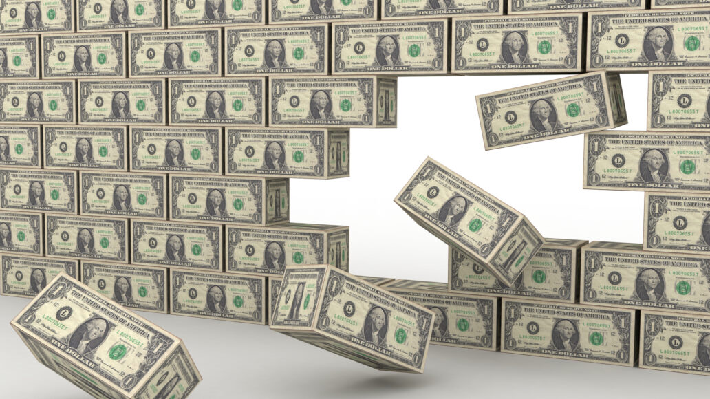 A 3D image of a wall made of US one-dollar bills, with several blocks falling from the right side, suggesting construction.
