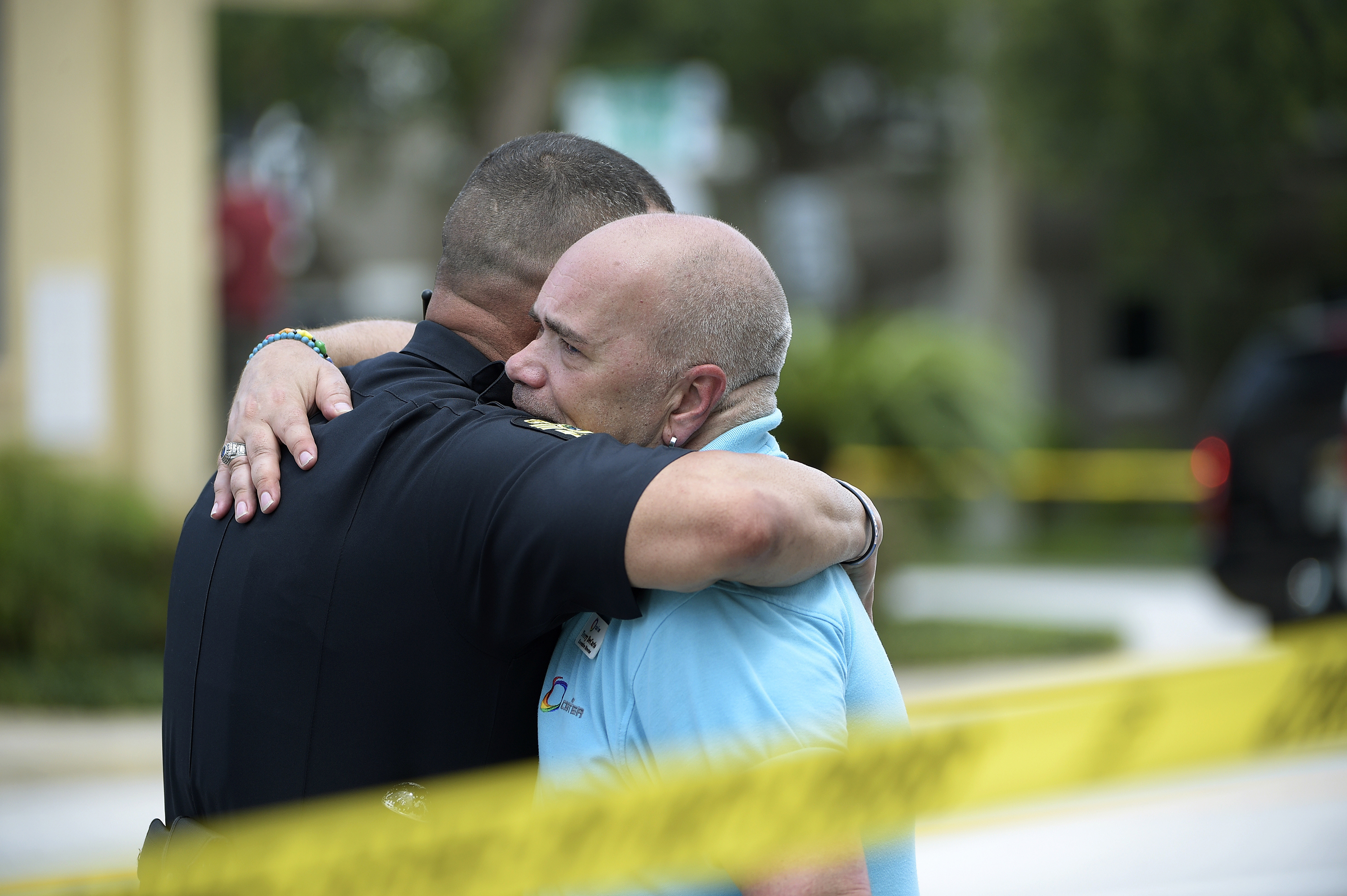 A police officer comforts Terry DeCarlo, right, executive director of the GLBT Community Center of Central Florida, which had raised $300,000 through crowdfunding by mid-morning Tuesday.