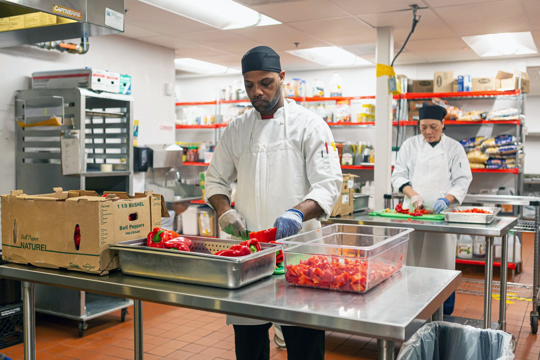 Photo of two cooks slicing red peppers