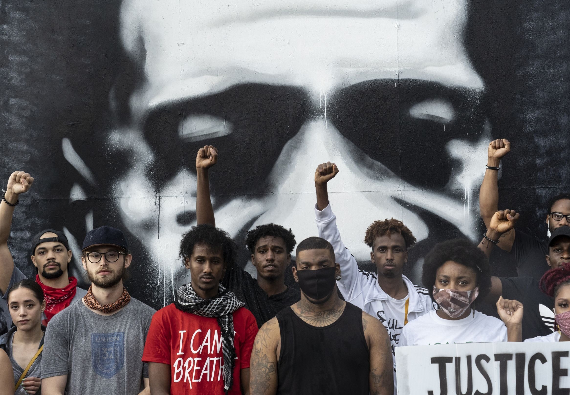People pose in front of a mural of African-American man George Floyd at the scene where he was pinned down by a police officer kneeling on his neck before later dying in hospital, in Minneapolis, Minnesota, United States.
