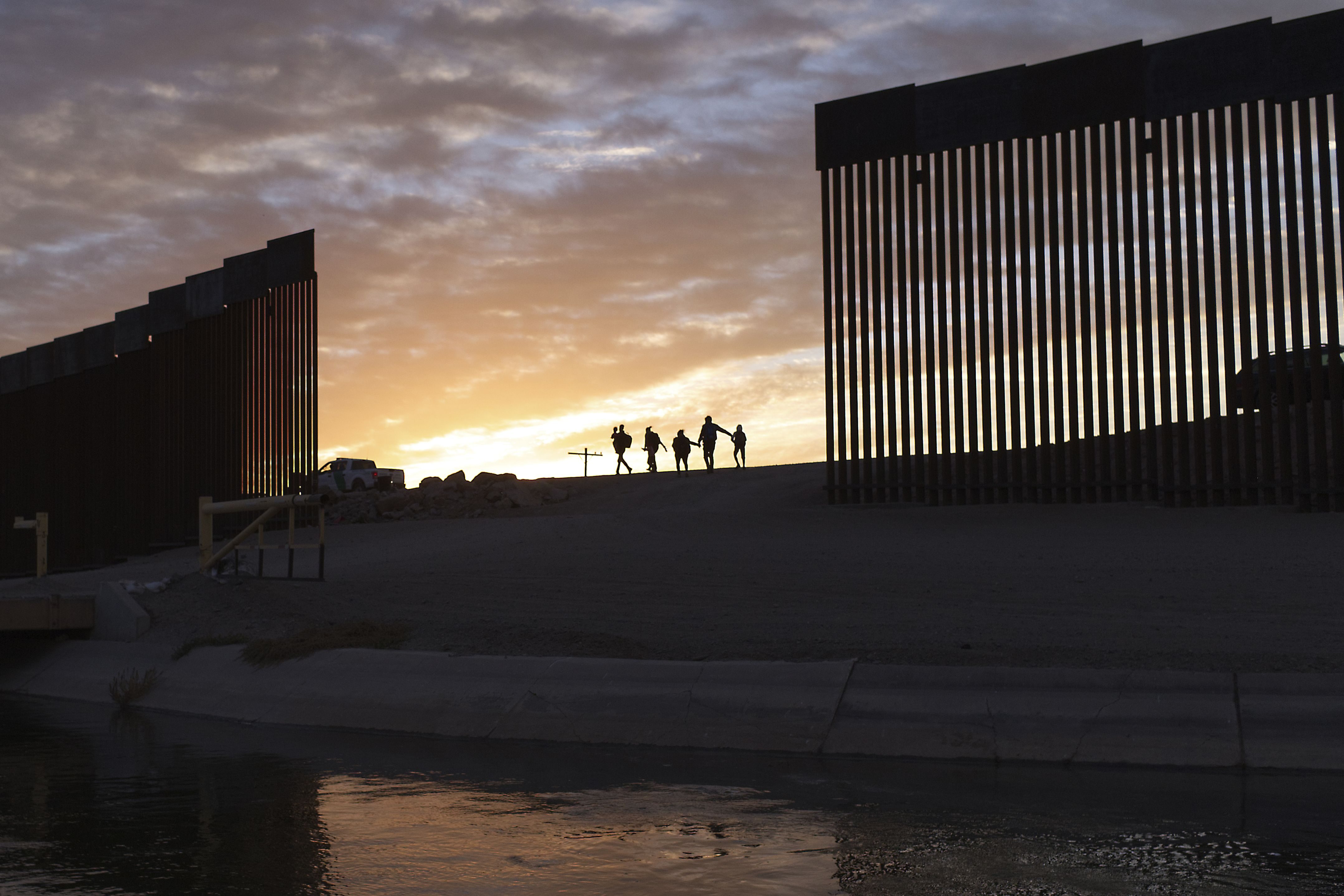 FILE - A pair of migrant families from Brazil pass through a gap in the border wall to reach the United States after crossing from Mexico to Yuma, Ariz., to seek asylum on June 10, 2021. The National Association of Immigration Judges on Thursday, July 21, 2022, asked the federal government to restore its recognition after the Trump administration stripped its official status, and the system's chief judge resigned after two years on the job. The two developments underscore political uncertainty at a critical time in the Justice Department's Executive Office for Immigration Review, which runs the courts. (AP Photo/Eugene Garcia, File)