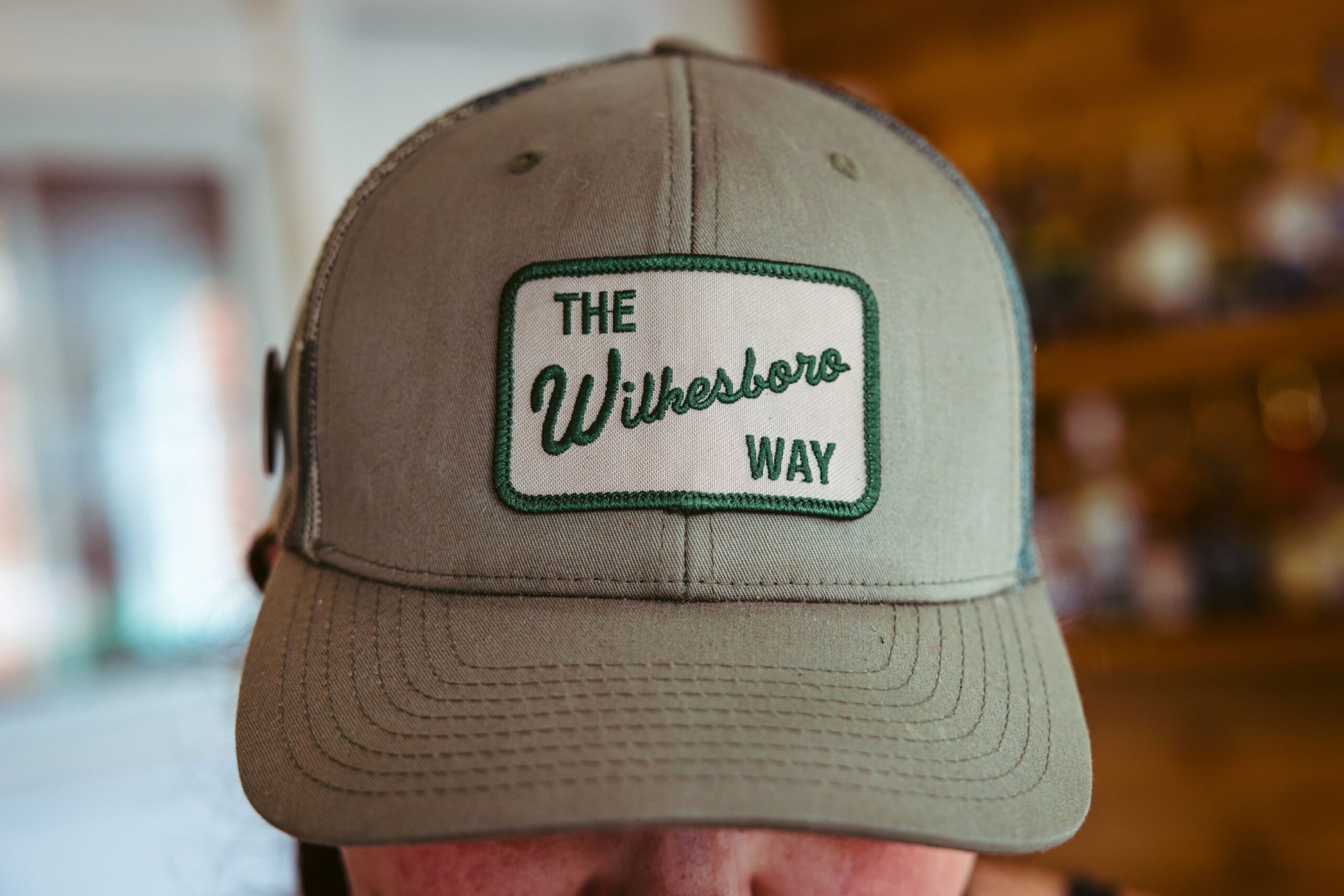 WILKESBORO, NC - MARCH 3:  L.B. Privette wears a hat the reads “The Wilkesboro Way” at the outdoor bar at the cocktail lounge she co-owns called Merle’s in downtown Wilkesboro, NC on March 3, 2024. She got the hat from the Wilkes Tourism Board and explained her meaning behind the hat is that “strangers are just future friends” and is her community building philosphy that she implements at her bar.   (Logan Cyrus for The Chronicle)
