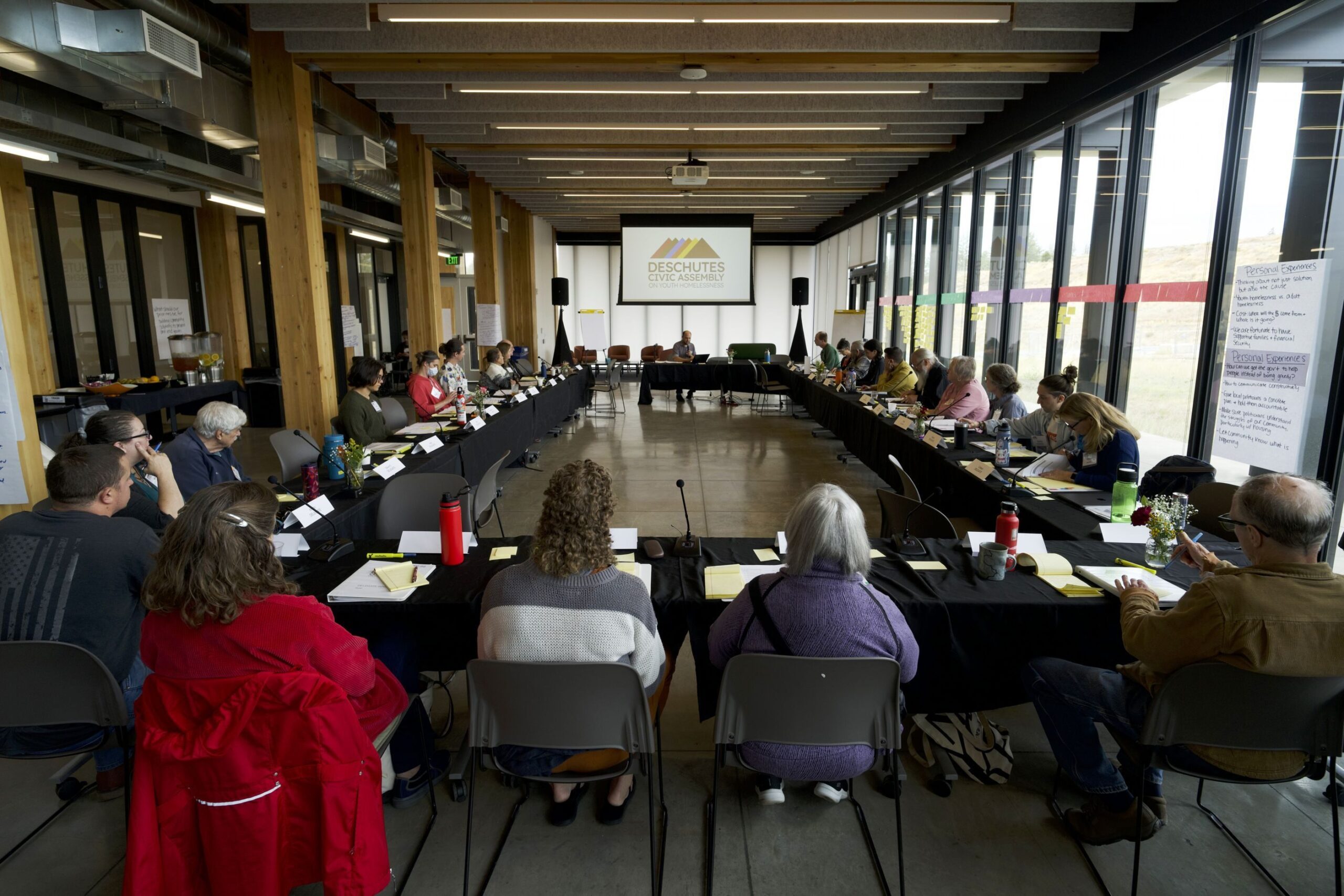 Participants gather around a large table for discussion during the Deschutes Civic Assembly on Youth Homelessness at the Oregon State University Cascades campus on Sept. 15, 2024.