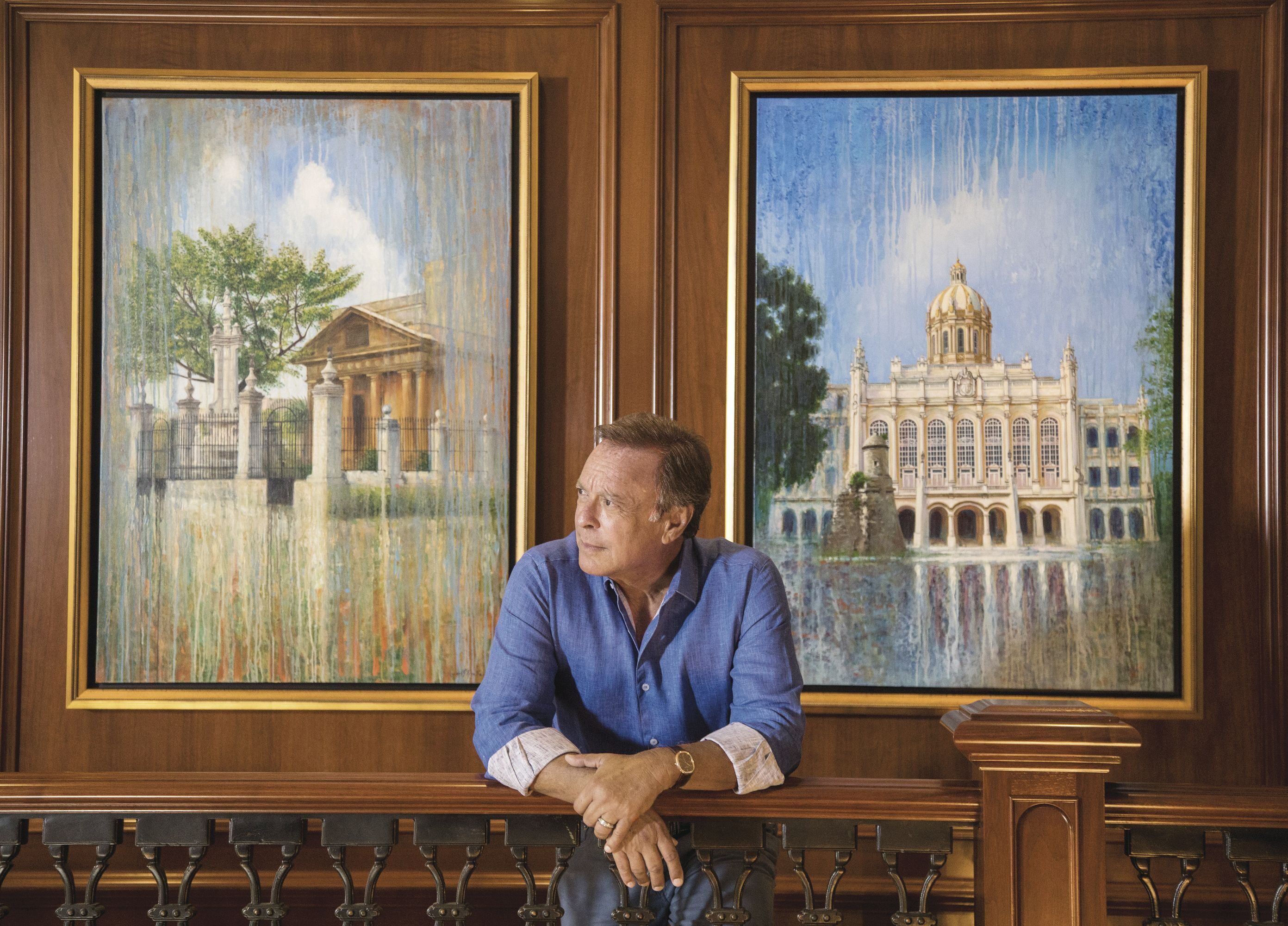 Miguel Fernandez at his Florida home, with paintings of Cuban landmarks.