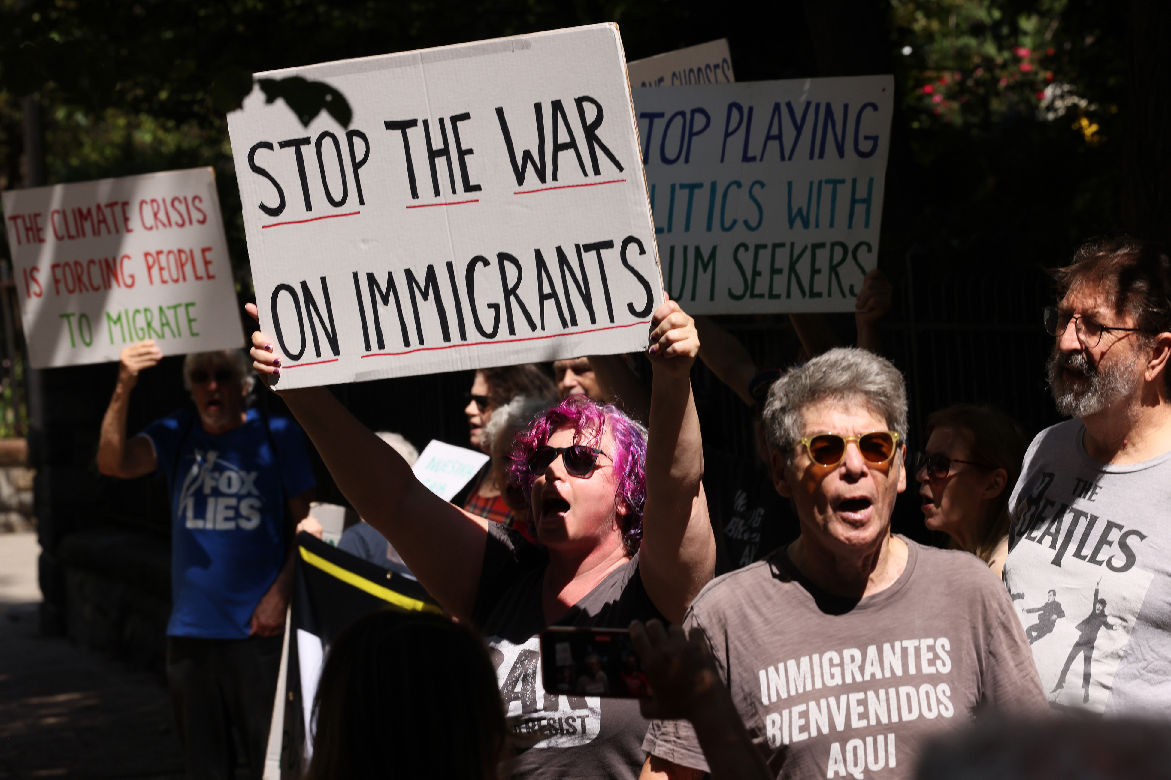 Counter protesters hold up signs as people participate in an anti-migrant rally and protest outside of Gracie Mansion on August 27, 2023 in New York City. 