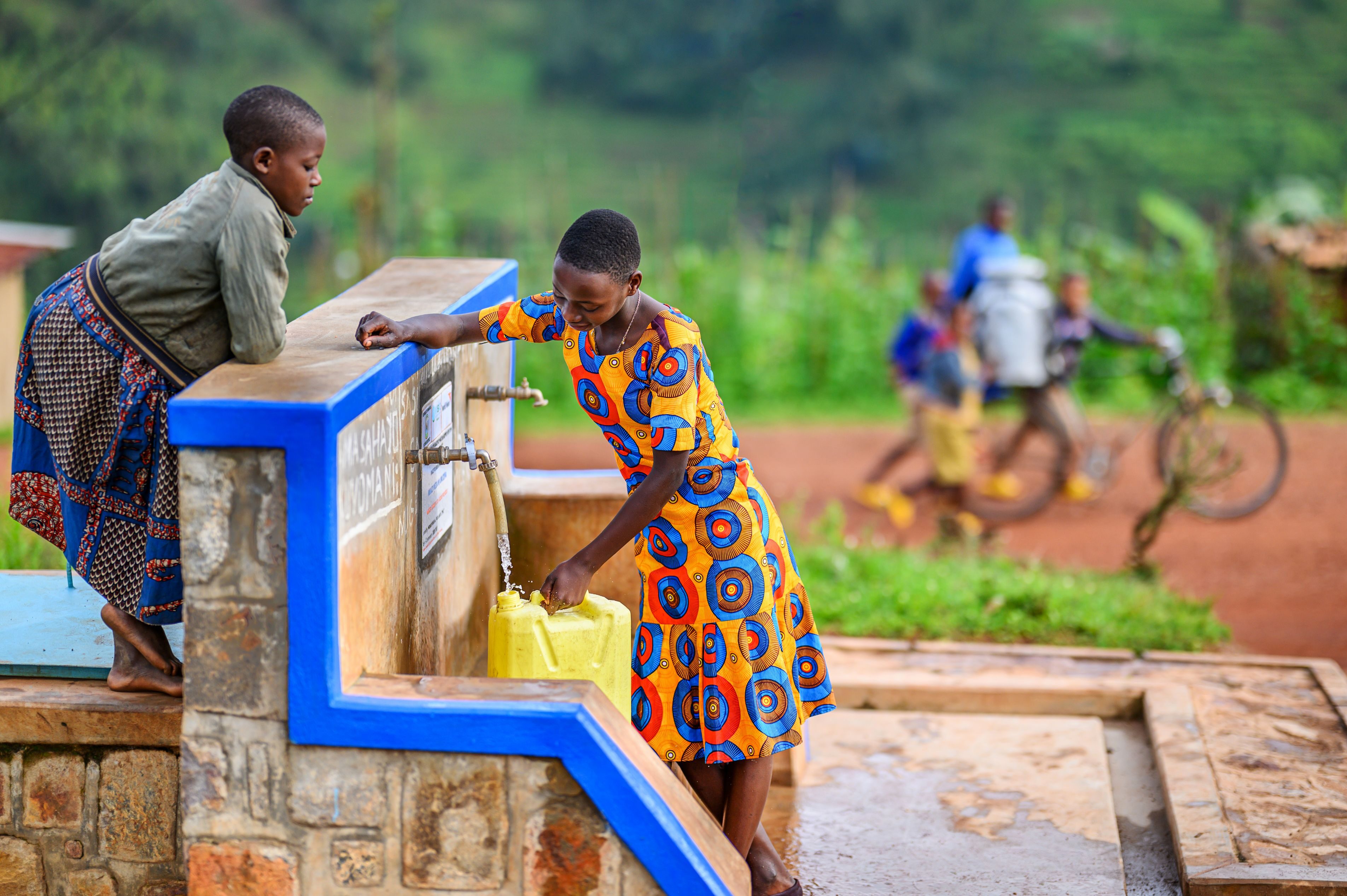 Merci and her best friend Sada (wearing olive-colored jacket) chat as Merci fills her jerry can with clean water at the World Vision communiy water taps, just a few minutes walk from her home in Kageyo AP, Rwanda.
The lives of Merci, 13, and her family, were changed dramatically when water became available. In the past they had to walk 90 minutes down steep hillsides to reach a water source.