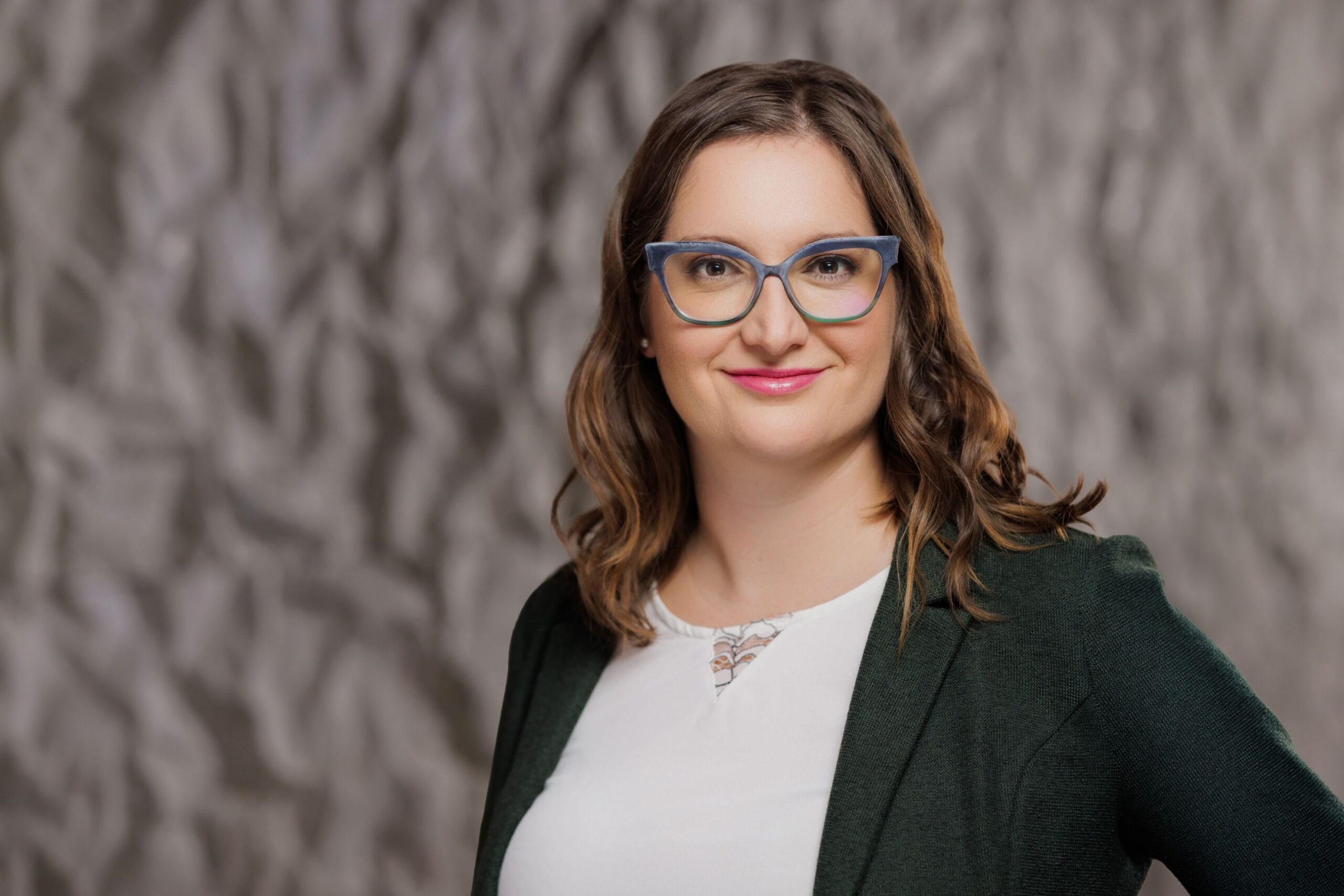Sarah J. Wilber, Vice President, Capital Campaign &amp; Strategic Planning at The John F Kennedy Center for the Performing arts, appears inside the Justice Forum in the REACH at The Kennedy Center. Wilber stands before a material called “crinkle concrete” specially designed for spaces inside the building. (Yassine El Mansouri, The Kennedy Center for the Performing Arts)