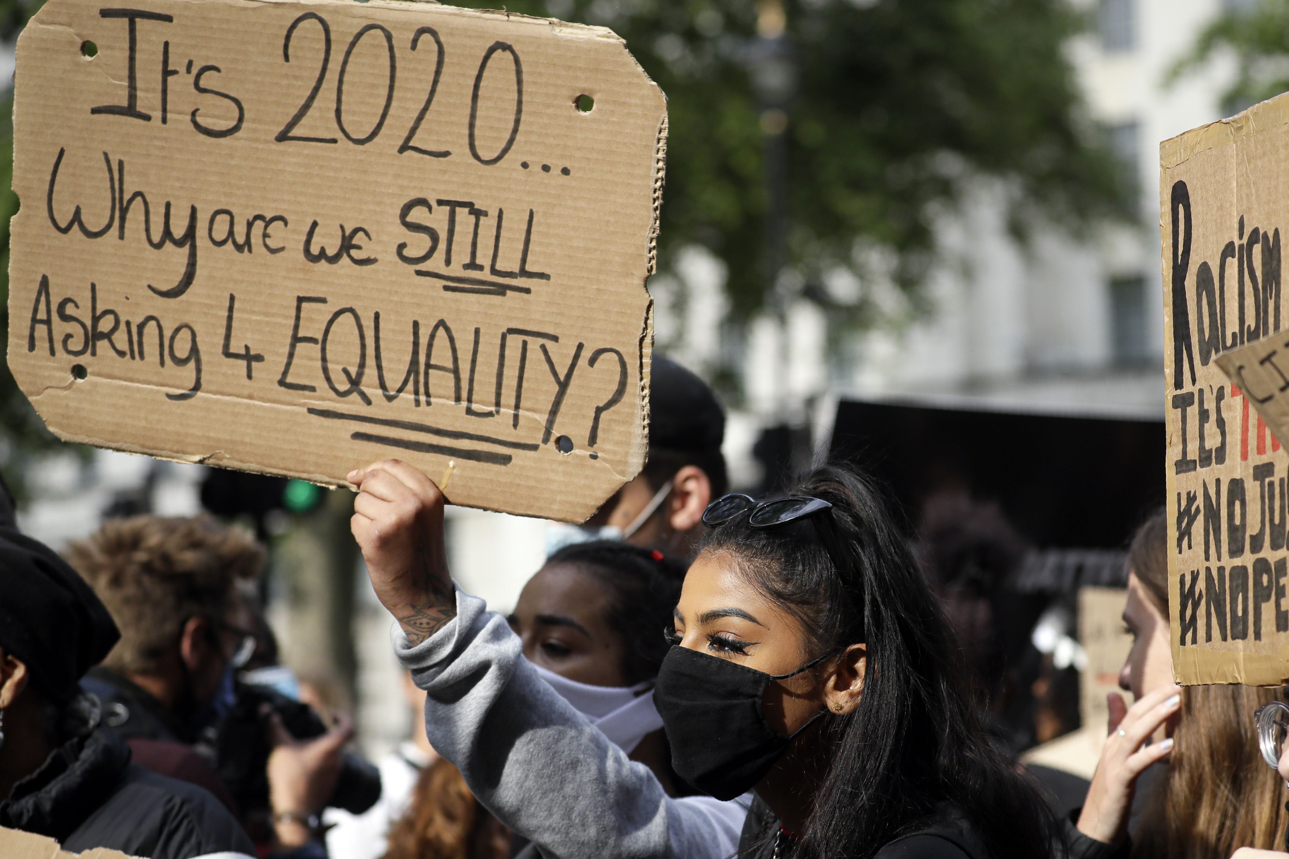 Protestors lift signs during a rally to commemorate George Floyd on the day of his funeral, June 9, 2020.