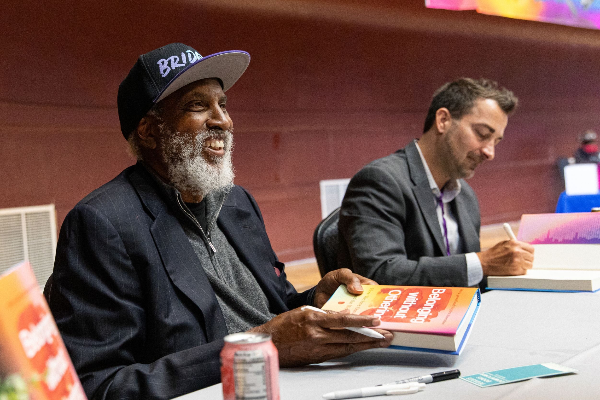 john a. powell, left, and Stephen Menendian sign copies of their book for guests at the Othering &amp; Belonging Conference in 2024.