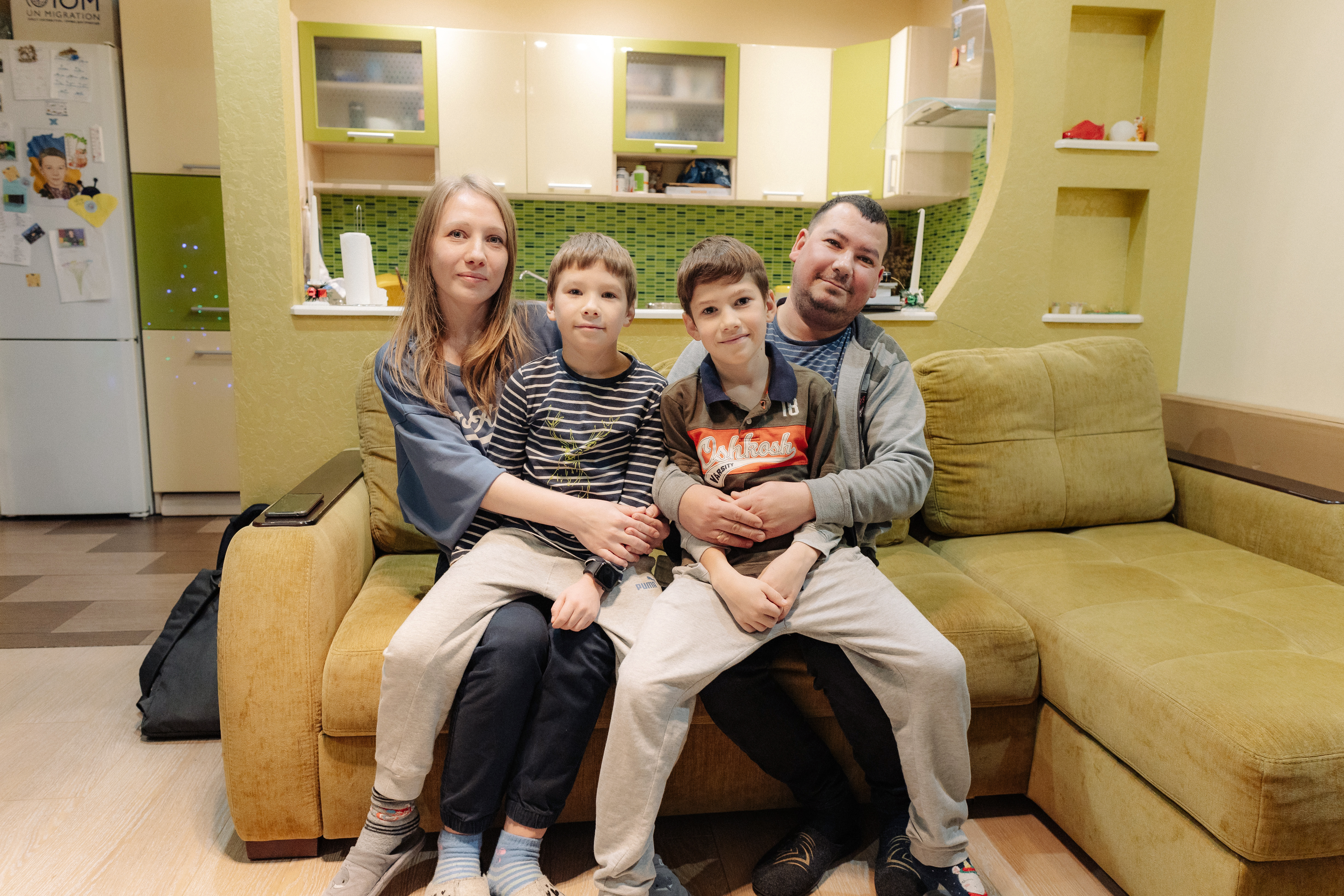 A family of four pose for a photo on a couch