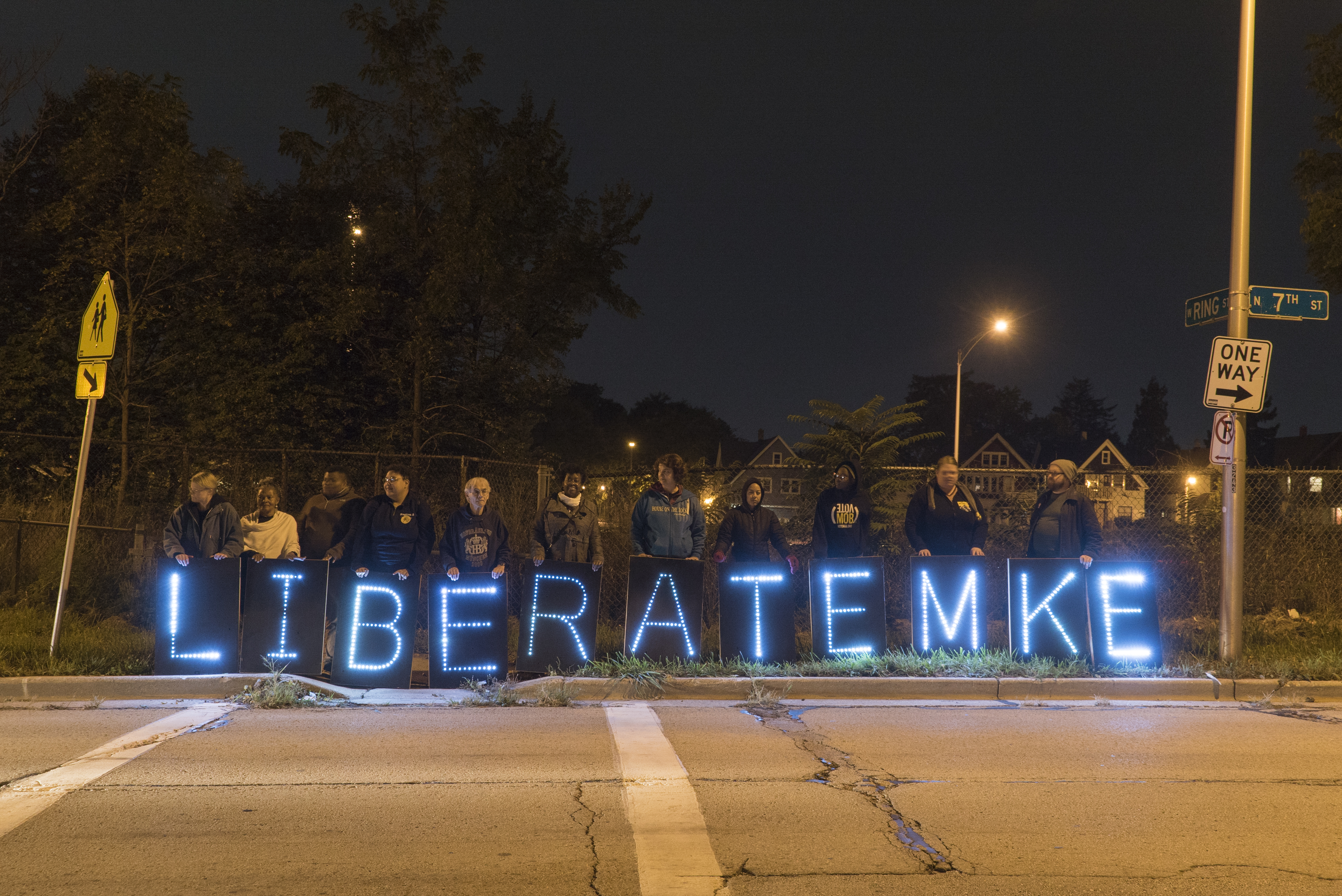 The City of Milwaukee budget invests heavily in police with roughly 46% of the budget going toward the Milwaukee Police. Here, members of LiberateMKE rally with lighted signage in the Riverwest neighborhood of Milwaukee.