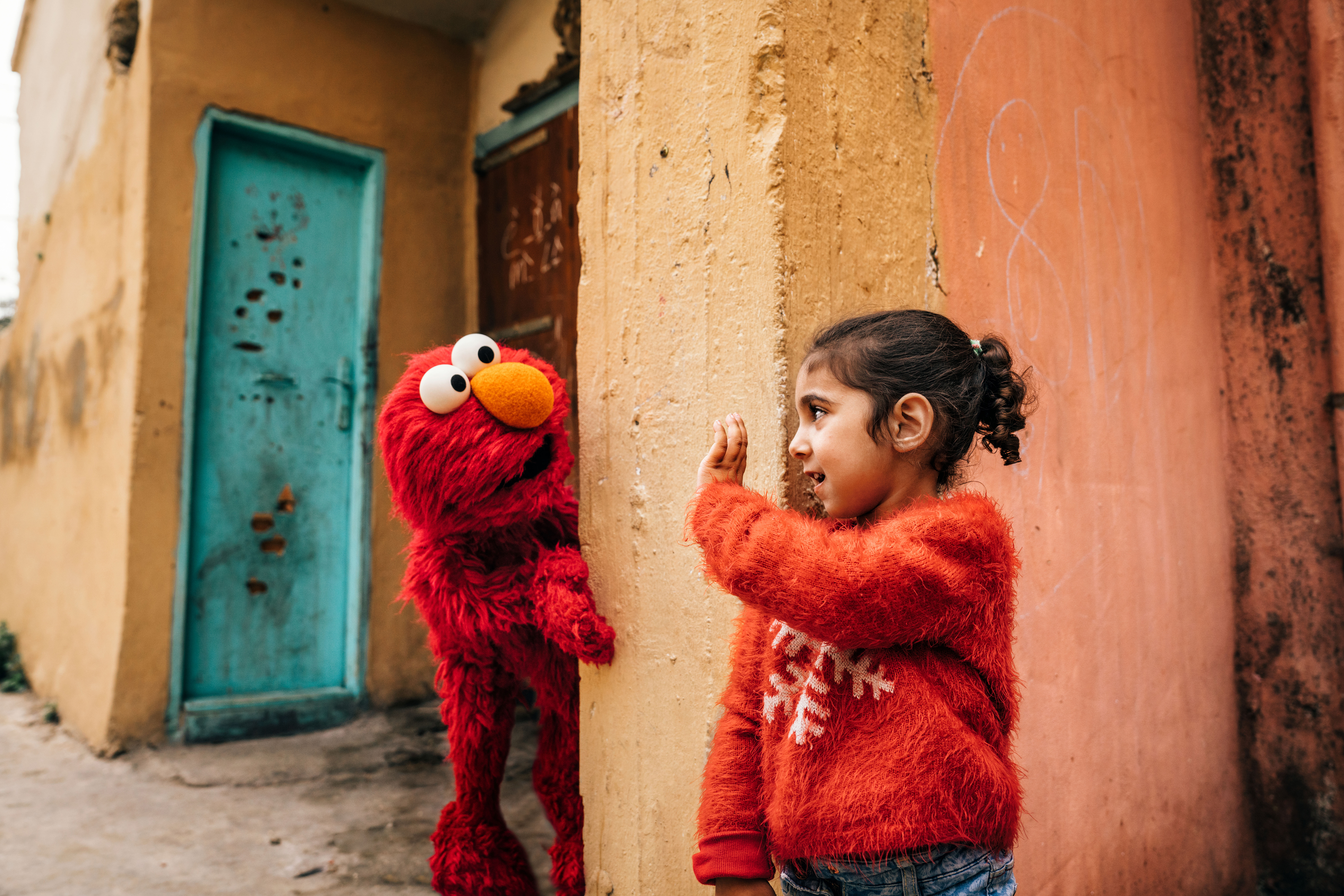 A young child waves at Elmo in Saida, Lebanon.