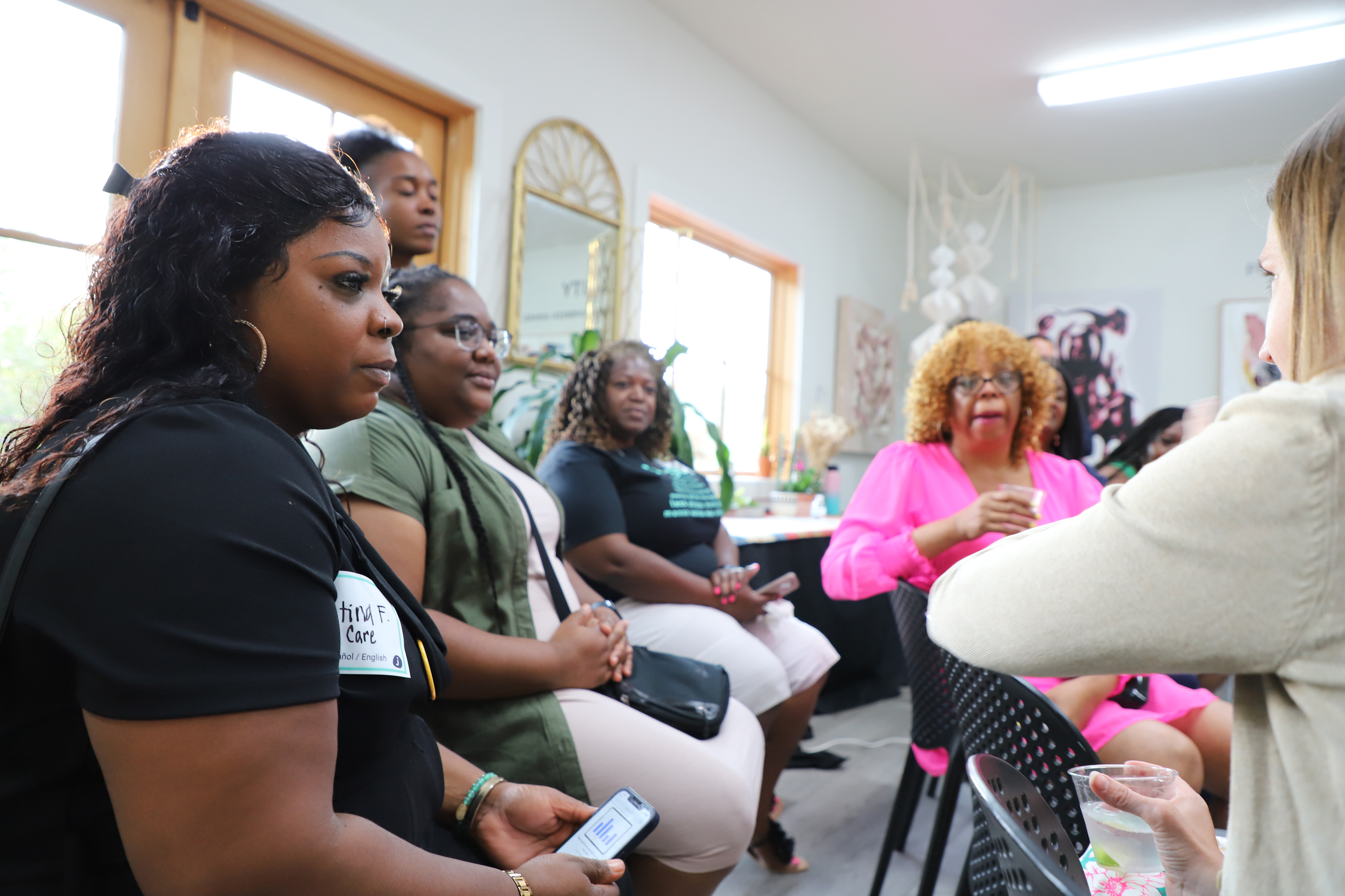 JUST Community launched a Saving Challenge before the summer began to leverage the power of community to create action and new habits. They offered a secured loan (capital) to be paid out at the end of the challenge. Each week they sent small pieces of content to encourage action (coaching). The Savings Challenge concluded with a large event (community) to celebrate their hard work. Here, women gather and talk at the Savings Challenge finale celebration. Credit: 