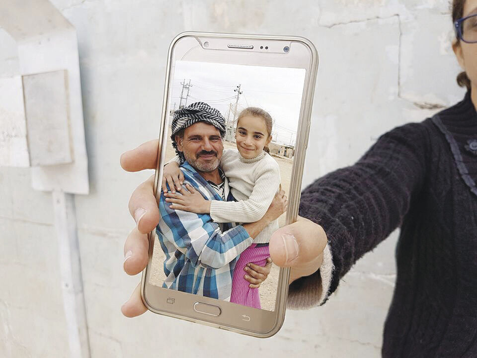 A refugee in Iraq shows a photo of members of his family who were reunited by the nonprofit Refunite.