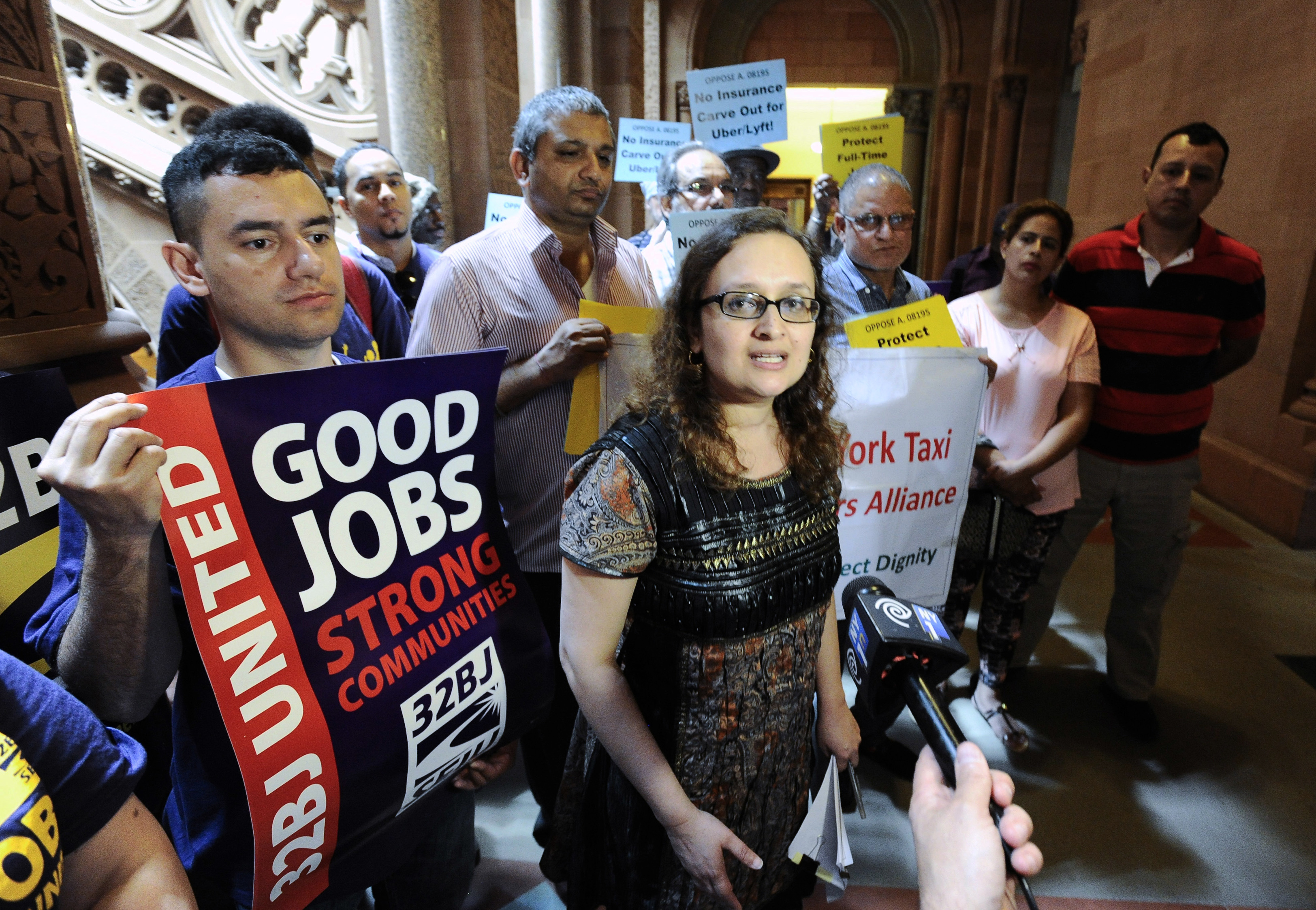 In this June 1, 2016 file photo, Bhairavi Desai, executive director of the New York Taxi Workers Alliance, center, speaks to reporters against allowing Uber and other app-based drivers to expand service to upstate New York, at the state Capitol on in Albany, N.Y. New York state lawmakers are considering legislation that would allow Uber and&nbsp;Lyft to expand into upstate cities like Buffalo, Syracuse, Albany and Rochester.&nbsp;The app-based ride-hailing services are now prohibited from operating outside of&nbsp; the New York City area. (AP Photo/Hans Pennink, File)