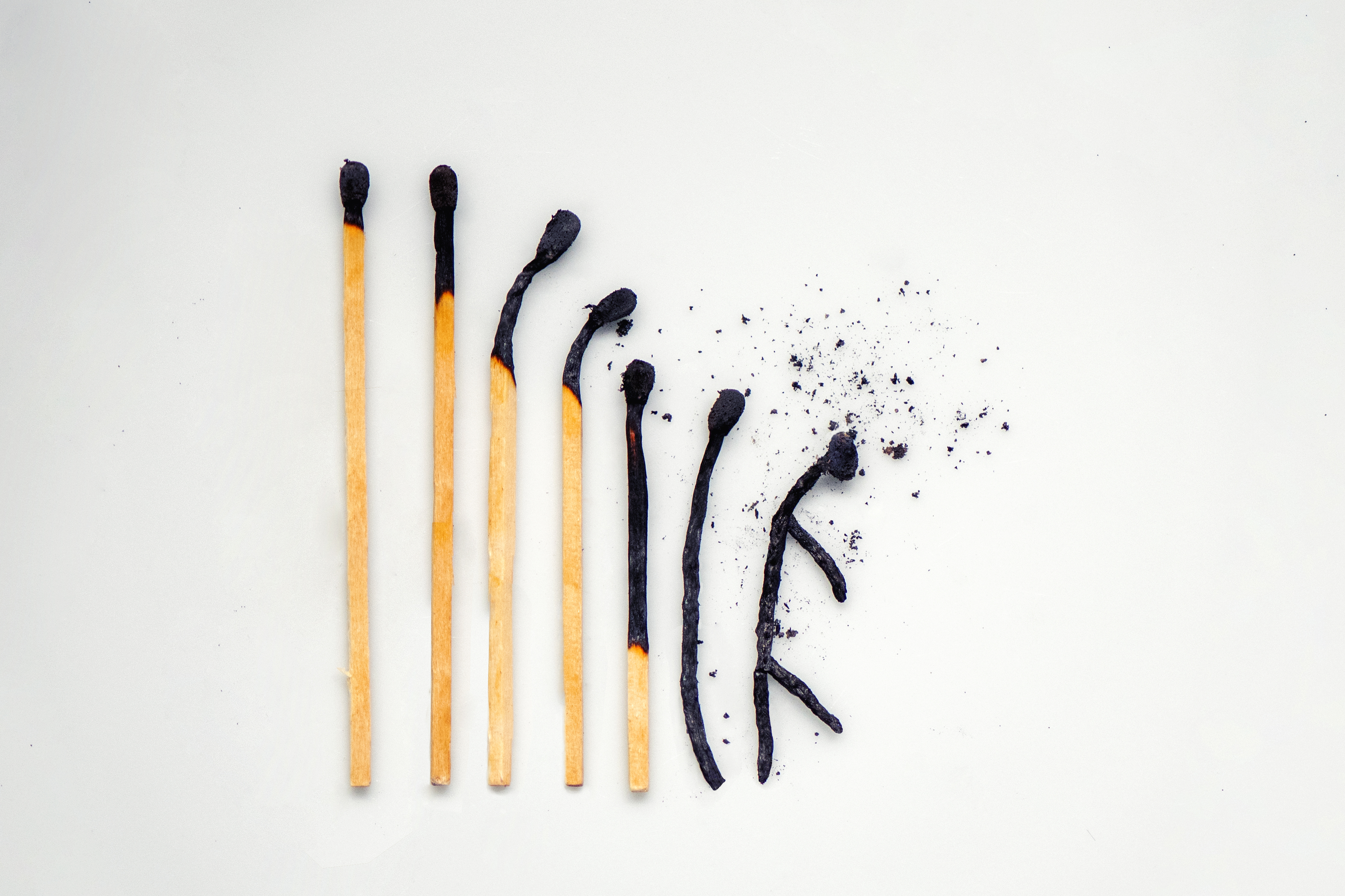 Close-up of burnt matches in order from largest to smallest, with the last one in the shape of a person symbolizing burnout.