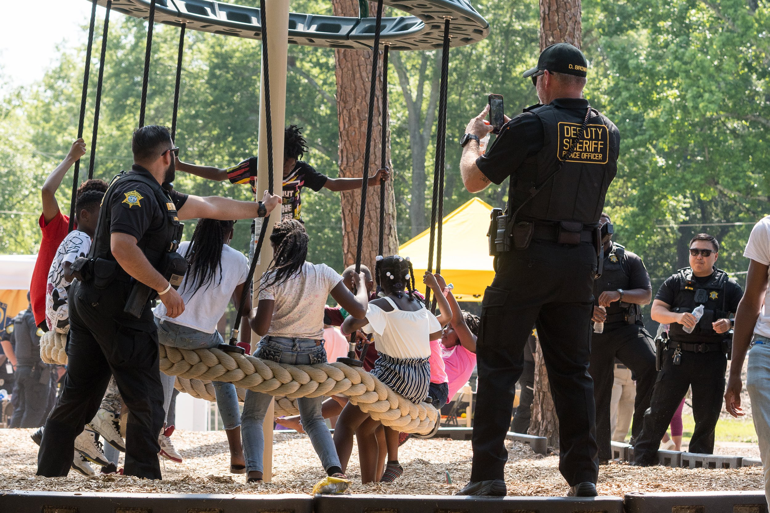 Richland County Sheriff Deputy J. Cuzzupe and Lt D. Brown and Lt. M. Kim in the background with children on playground.