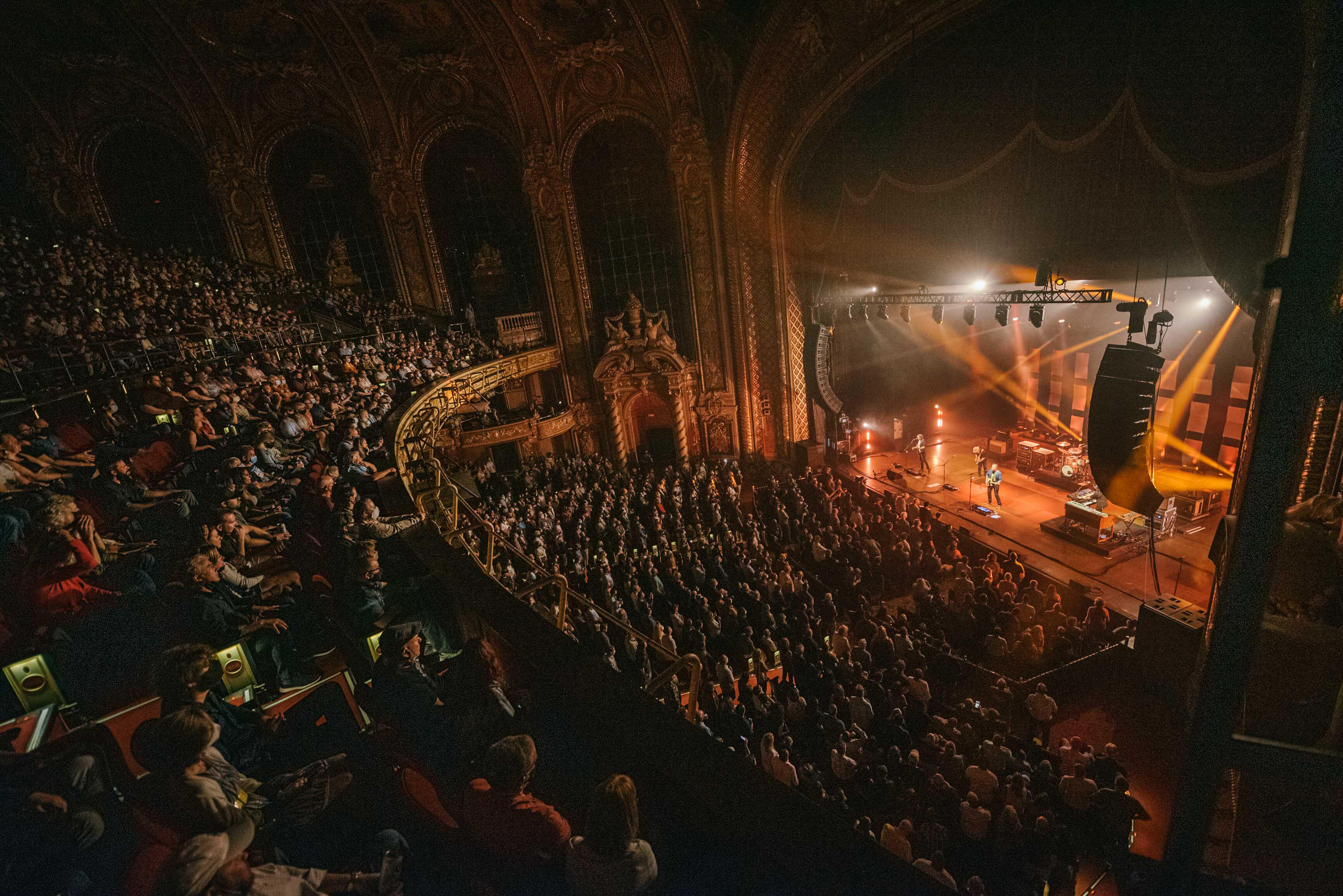 Photo of a darkened theater hall and lighted stage with performers at the Boch Center in Boston. 