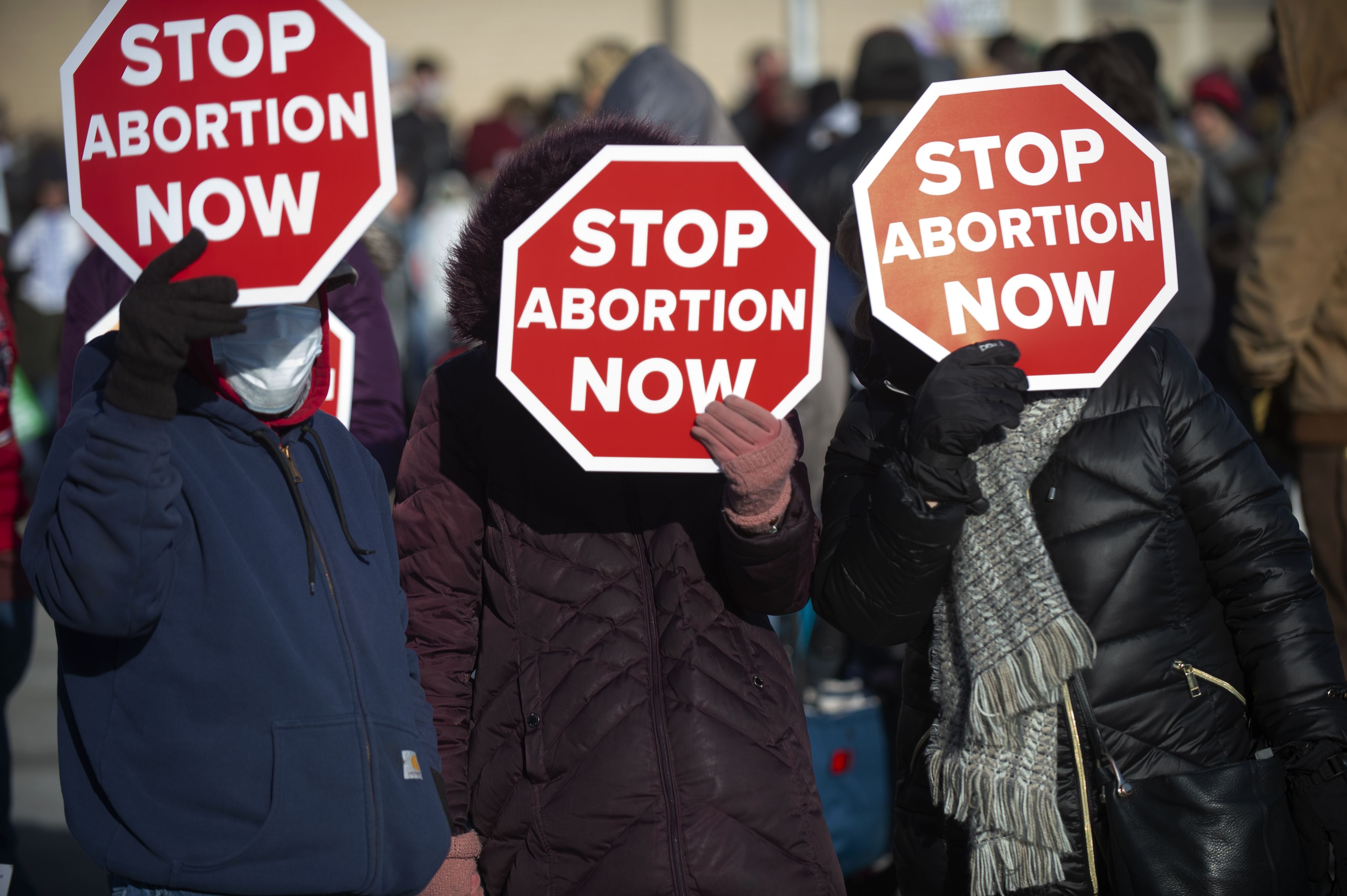 Anti-abortion advocates use their signs to block the sun during a rally near the north steps of the Nebraska State Capitol, in Lincoln, Neb.