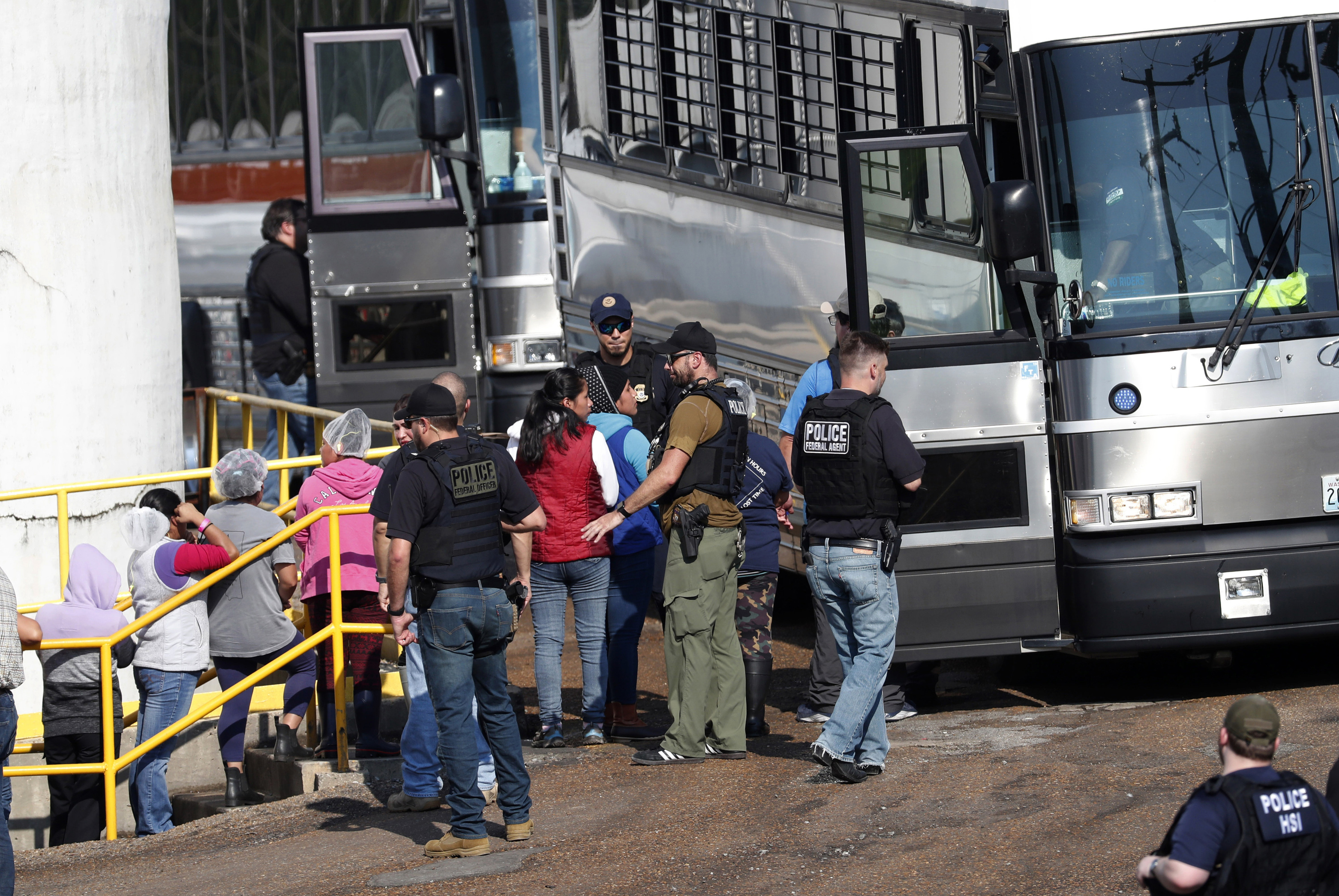 Workers are escorted into a bus for transportation to a processing center following a raid by U.S. immigration officials at a Koch Foods Inc., plant in Morton, Miss. on Aug. 7, 2019. Immigration agents arrested 680 Latino workers in a massive workplace sting at seven Mississippi chicken processing plants.