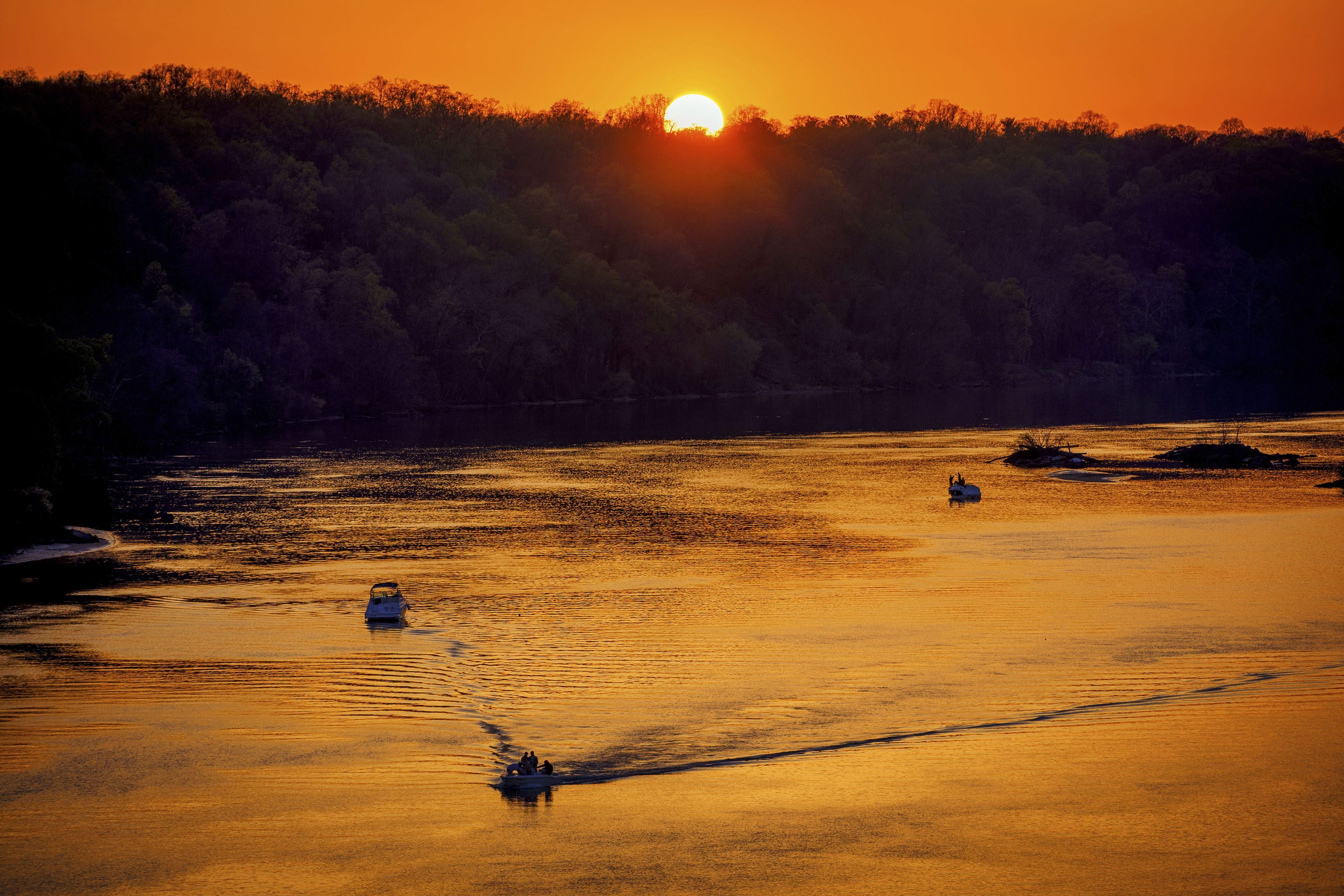 Boaters cruise along the Potomac River at sunset on a warm spring evening in Washington, D.C.