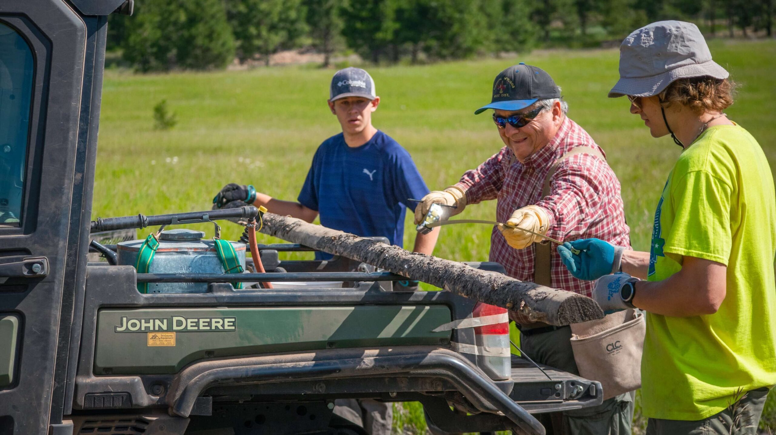 Three people unload materials from a vehicle. 