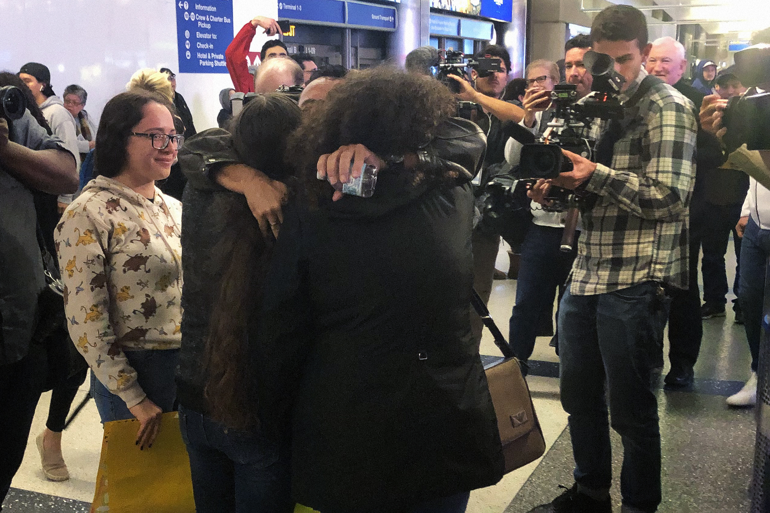 People hug in an airport