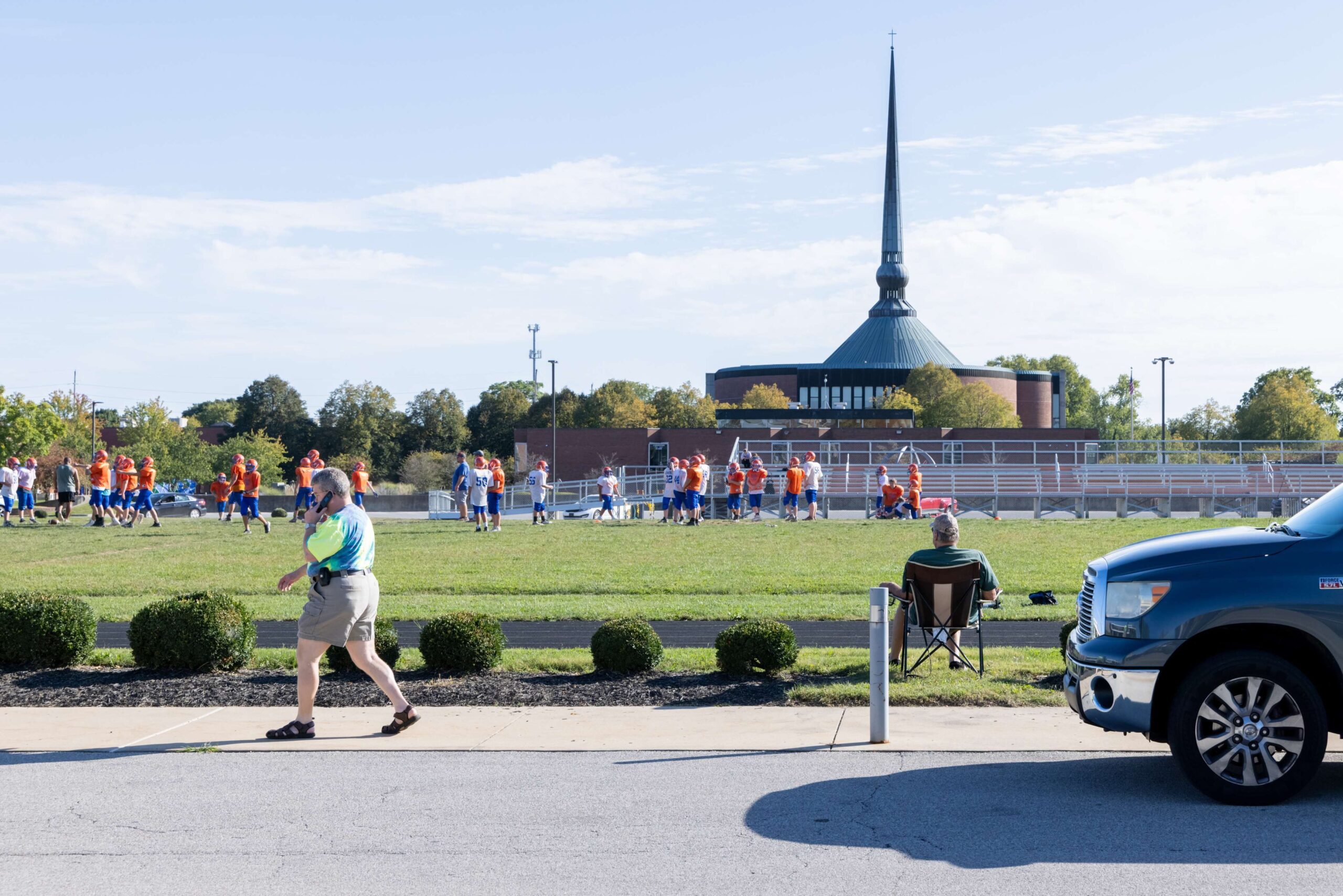 A football team practices at Central Middle School, with St. Peter’s Lutheran Church, a design by Gunnar Birkerts in 1988, rising in the background.