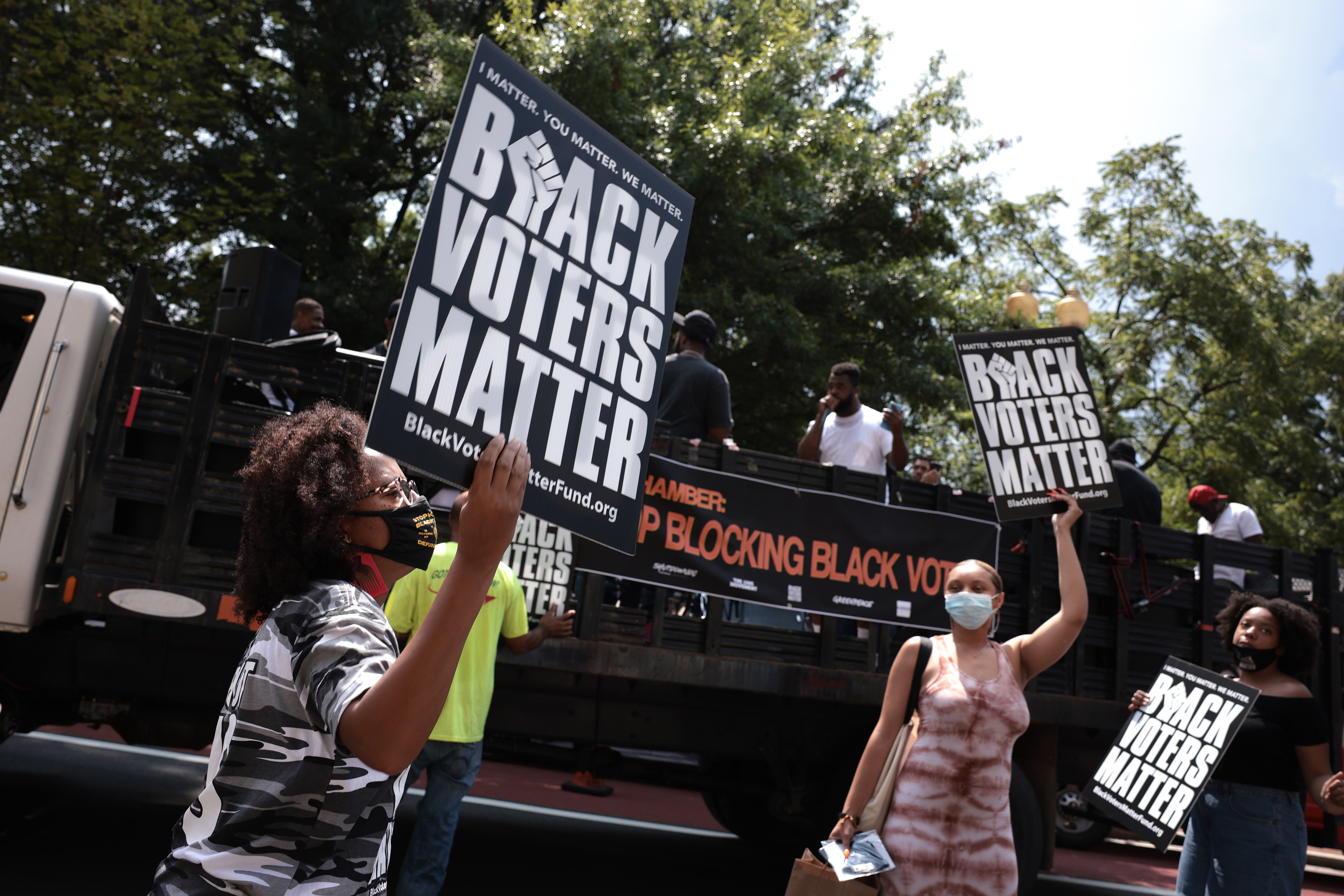 Demonstrators hold up signs during a live performance by the organization Long Live GoGo at a voting rights protest outside the U.S. Chamber of Commerce Headquarters on August 26, 2021 in Washington, DC. The voting rights protest was held in partnership with Black Voters Matter, The Live Movement, Greenpeace, ShutDown DC, and other organizations who say the Chamber of Commerce opposes the For The People Act.