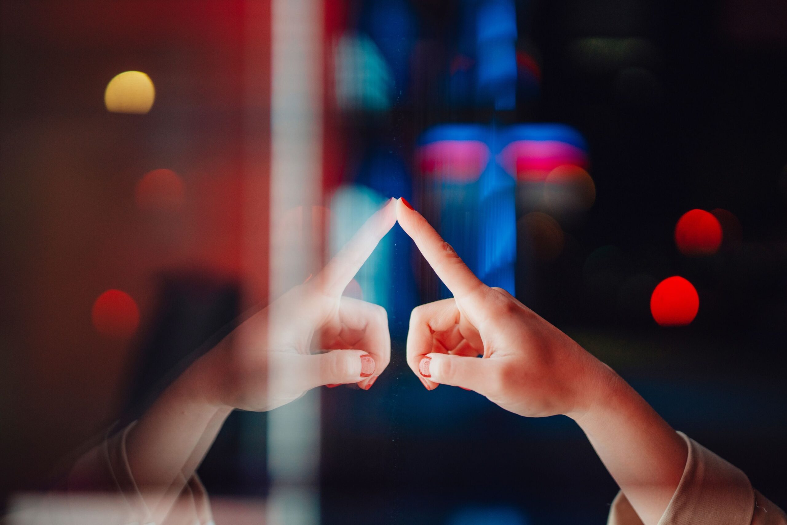 Close-up shot of female finger controlling touch display screen in a dark environment, with bokeh light in the background.