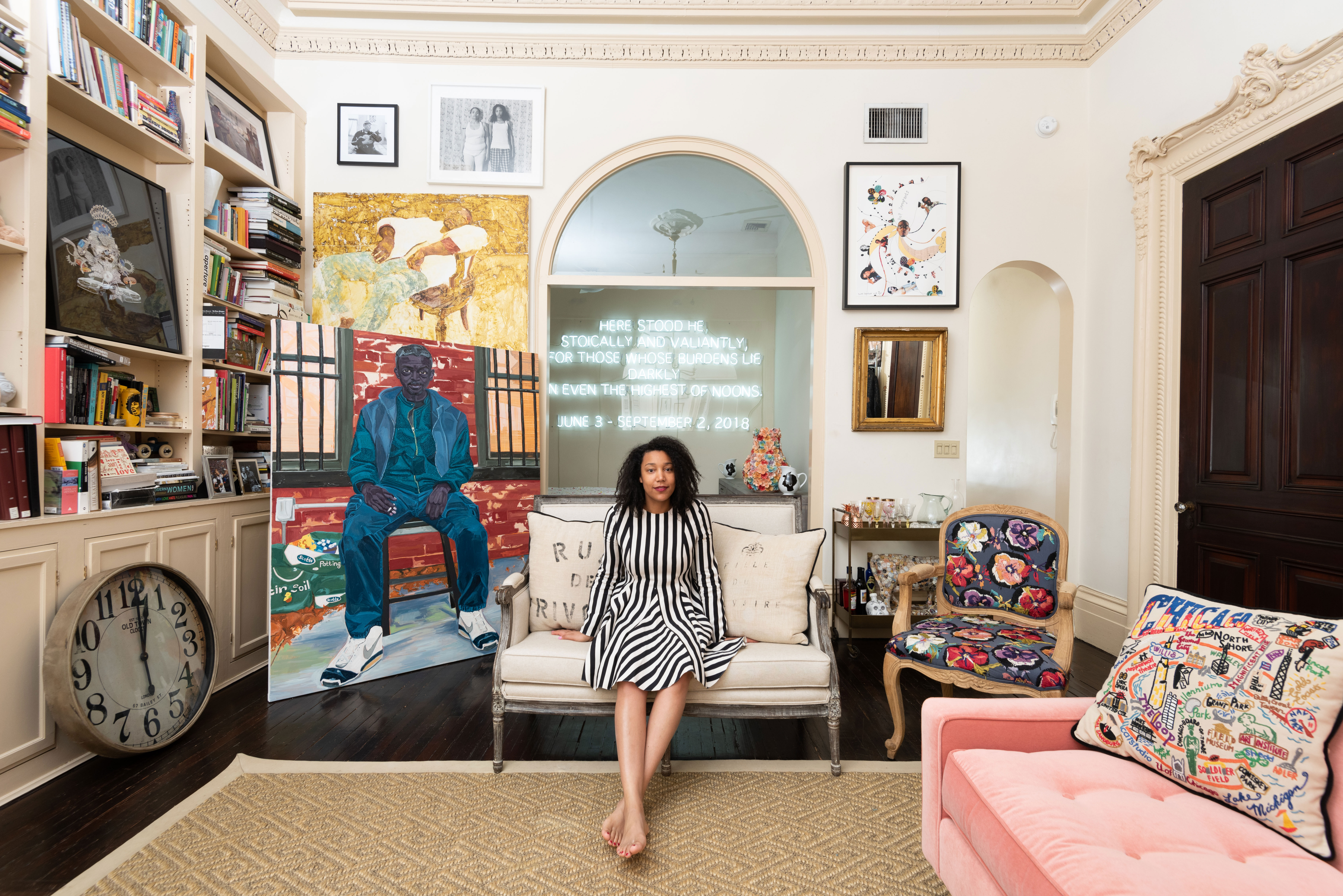 Victoria Rogers sits on a couch in a large room filled with art objects. 
