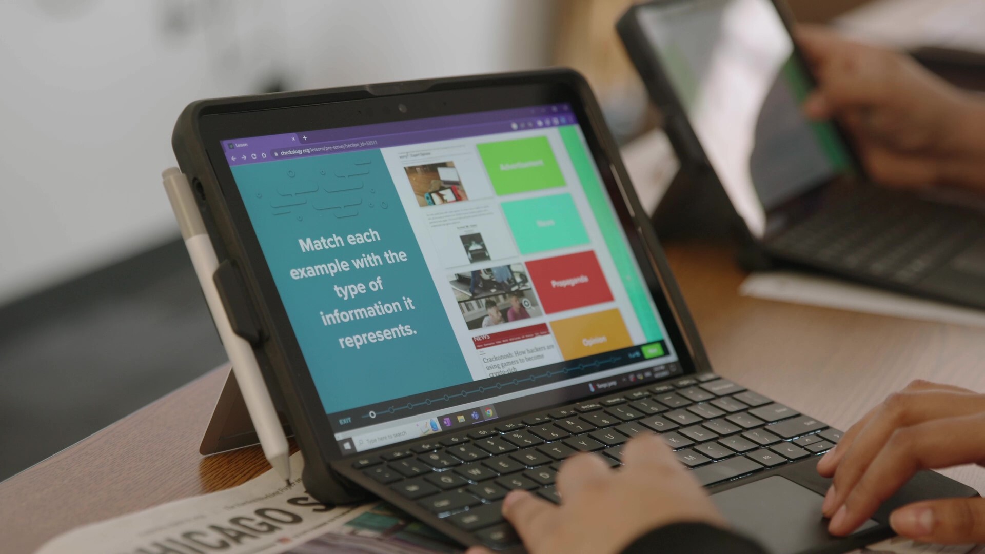A close-up image shows hands operating a laptop. The screen displays a program instructing users to “match each example with the type of information it represents.”